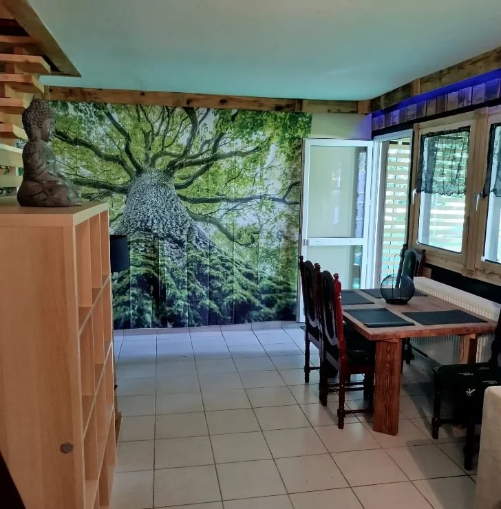 Modern office interior with large tree canopy mural on wall, wooden desk, chairs, cabinet, and glass doors with turquoise ceiling
