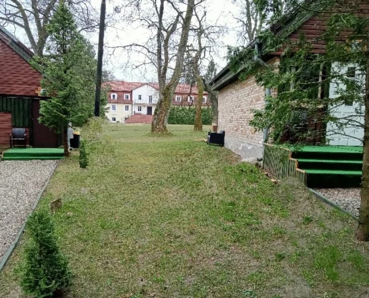 Green lawn courtyard between historic brick and stone buildings with bare trees and wooden benches
