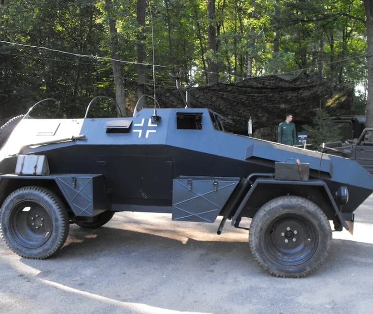 Blue and black armored military vehicle with cross insignia parked outdoors with trees in background