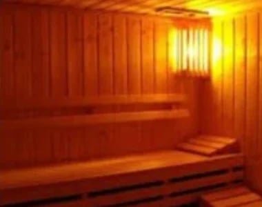 Interior of a sauna with wooden walls and bench, glowing with warm orange and yellow heat lighting
